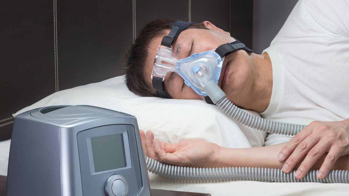 Person sleeping in his bed with CPAP machine