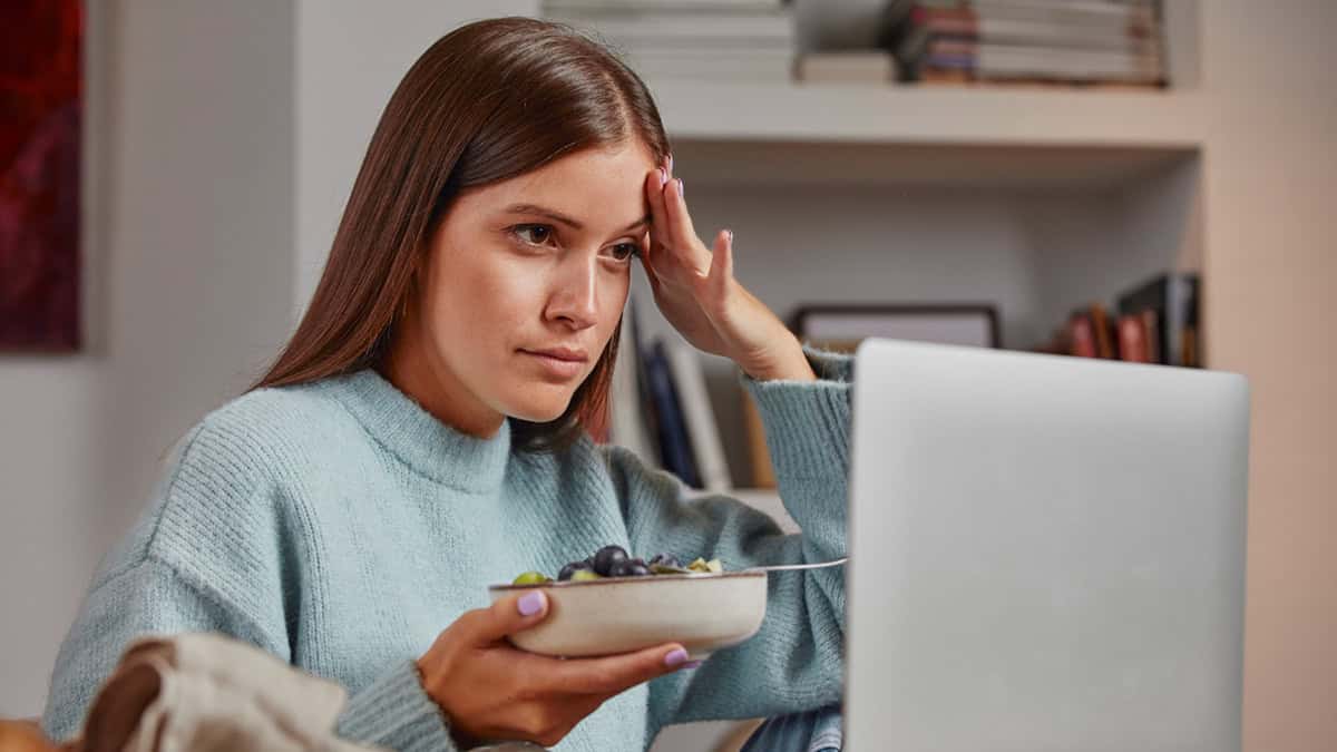 A stressed person with her laptop and a fruit bowl