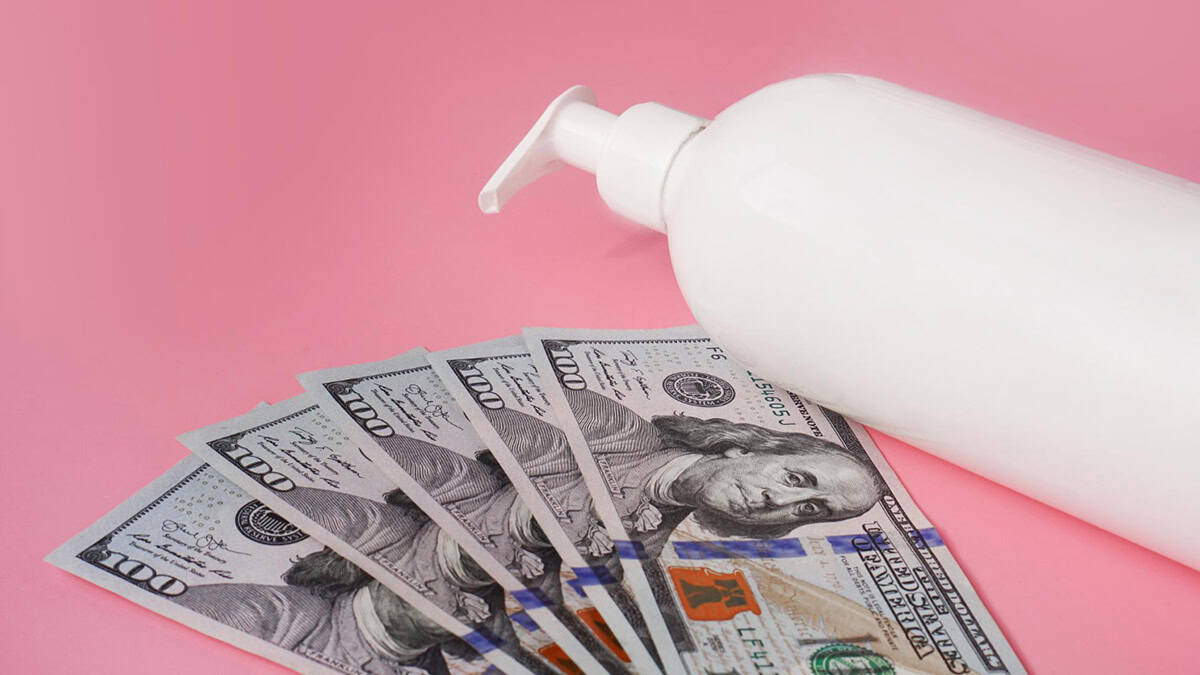 A bottle of lotion besides hundred dollar bills