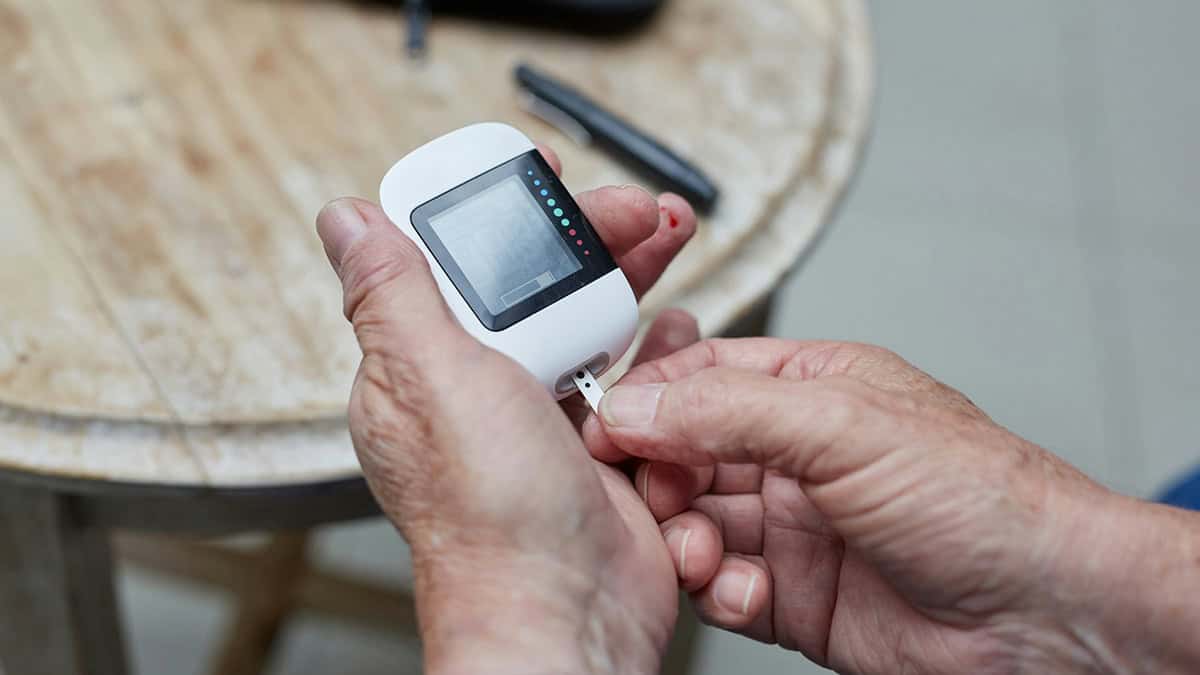 Person with glucometer checking blood sugar level