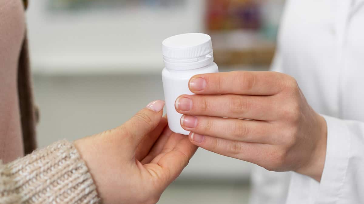 Pharmacist giving medication bottle to a person