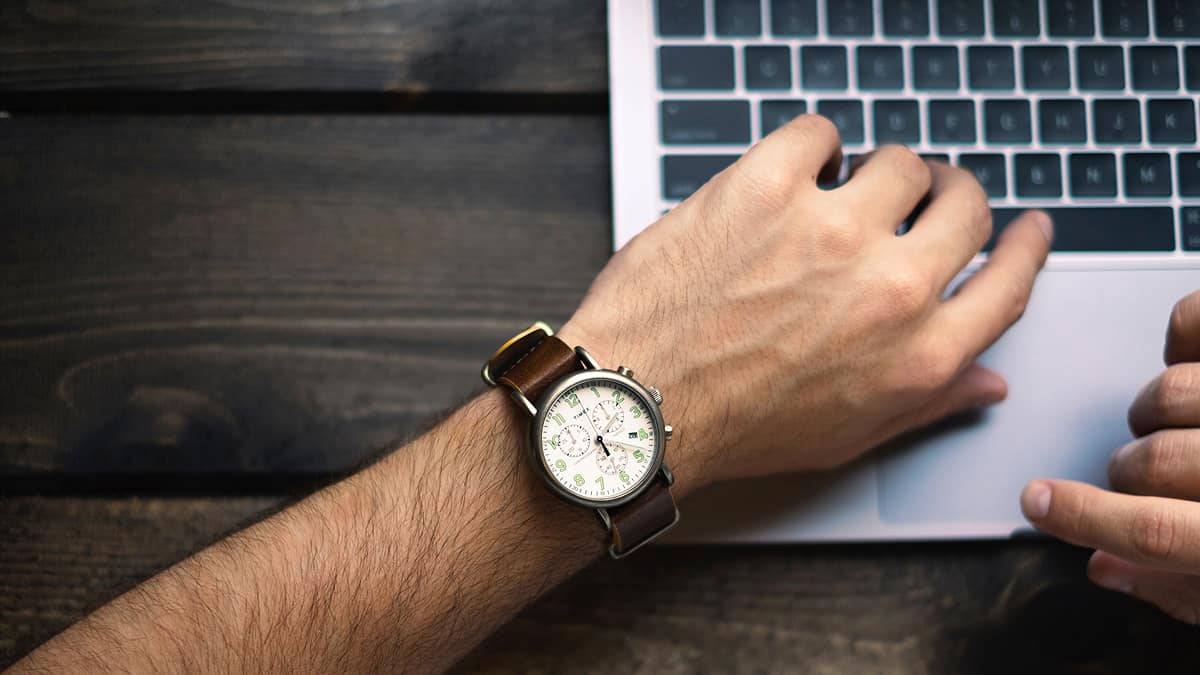 Man with a watch using a laptop