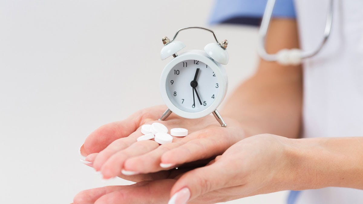 Doctor holding medication and clock